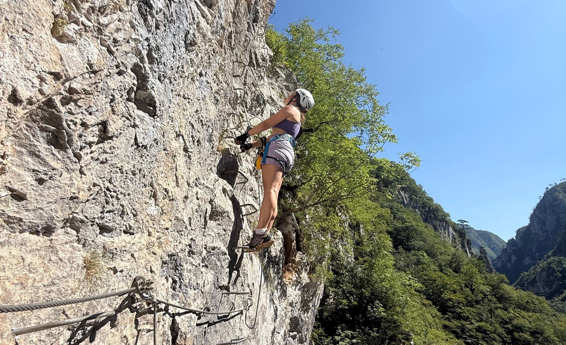 Climber on the rungs of the Via Ferrata Piva high above the green Piva canyon, Montenegro