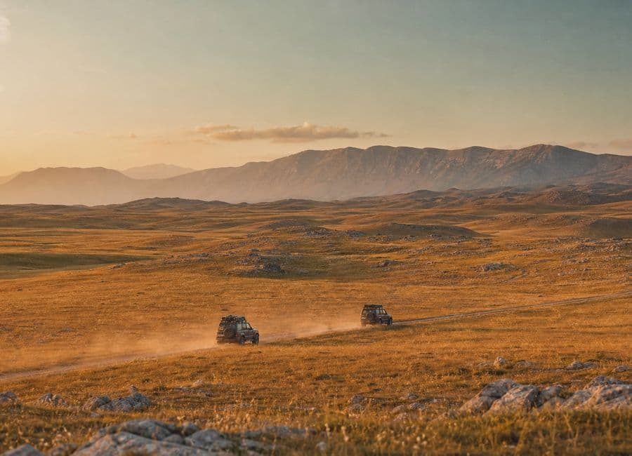 Two expedition vehicles crossing the open Livno plateau