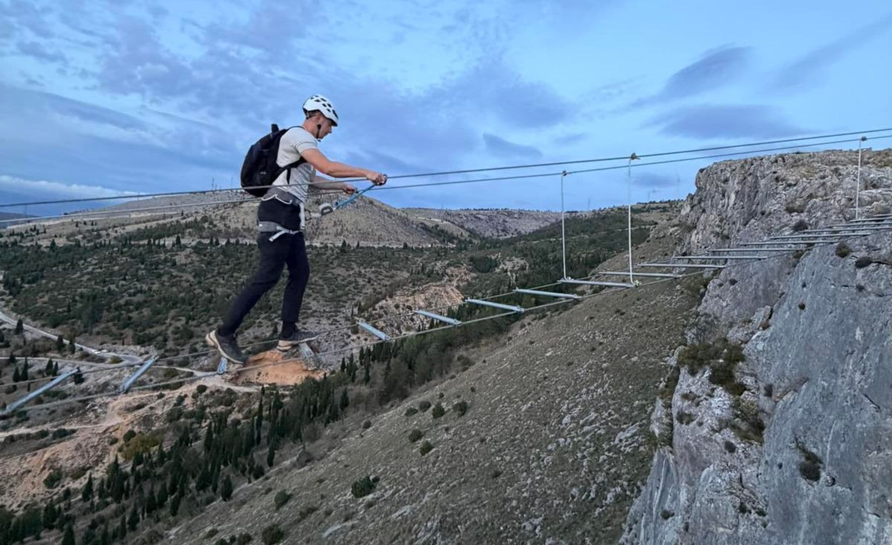 Climber crossing the suspension bridge on the Fortica via ferrata above Mostar at dusk