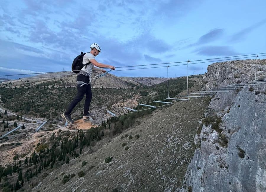 Climber crossing the suspension bridge on the Fortica via ferrata above Mostar at dusk